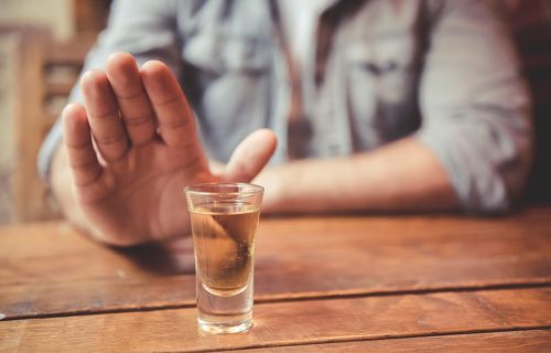 Cropped image of man showing stop gesture and refusing to drink