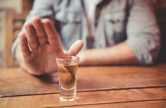 Cropped image of man showing stop gesture and refusing to drink