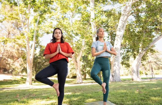 Women demonstrating a yoga movement during their exercise outdoors. This image is being used in the article, "Nitric Oxide for Heart Health: What It Is and How to Boost It”
