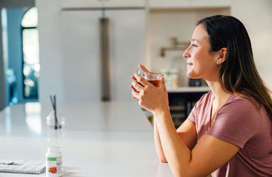 A woman drinking a cup of Herbal Tea Concentrate.