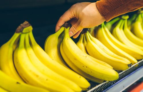 mans hand take bananas from shelf of store. healthy food. shopping concept