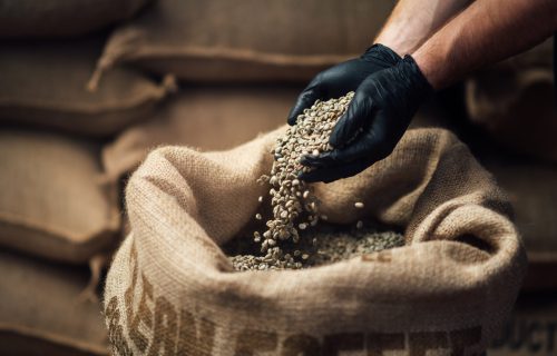 Raw,Coffee,Pouring,From,A,Handful,In,A,Bag,,Against